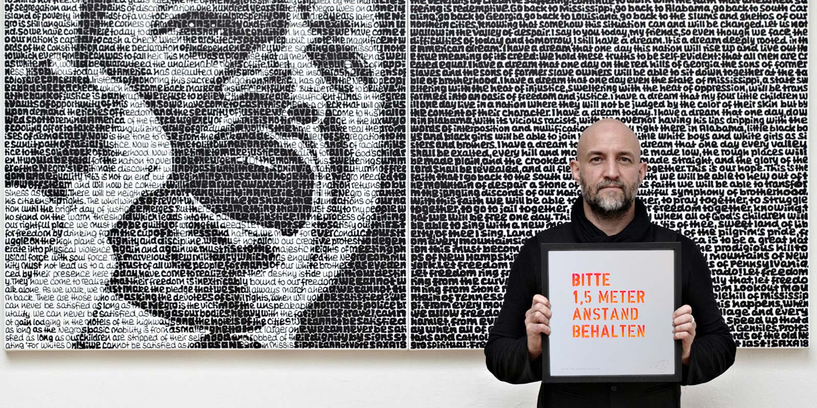 Saxa in Front of his Artwork, holding another Artwork in his hand